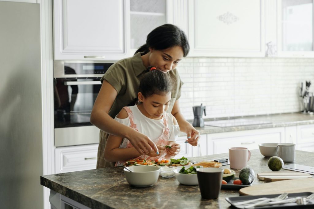 A woman cooking in a kitchen with her child